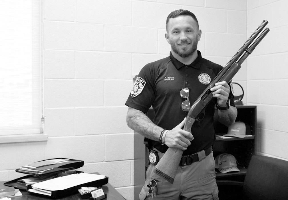 Kingfisher County Sheriff Aaron Pitts stands in his office with the gun initially labeled as missing in an audit by the State Auditor’s Office. (Jake Ramsey/Oklahoma Watch)