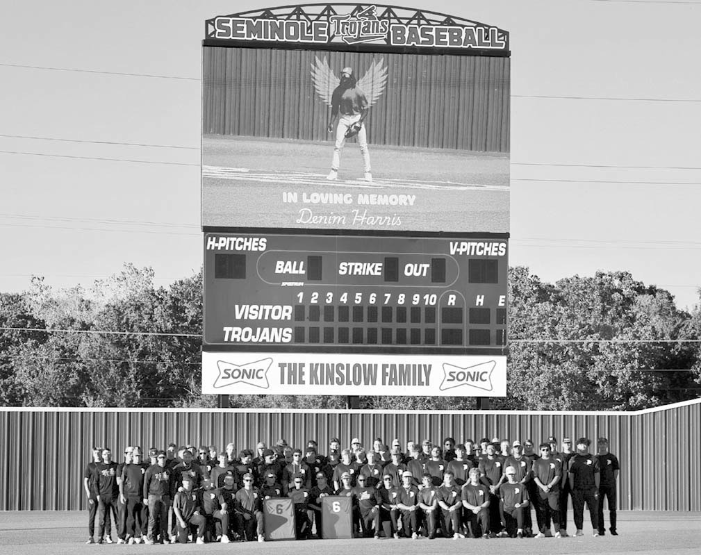 Above, Trojan Baseball players stand beneath the videoboard displaying a photo of teammate Denim Harris (pictured above left) as they hold framed jerseys later presented to his family. A candlelight vigil in honor of Harris was held Tuesday night at the B