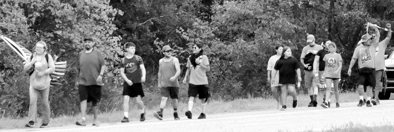 Left, participants in the annual “Every Child Matters Honor Walk” make their way up Highway 377 from the Mekusukey Mission Wednesday morning. The walk focuses attention on Native American children who were forced to leave their homes to attend residential boarding schools. (Photo by Bill Anderson)
