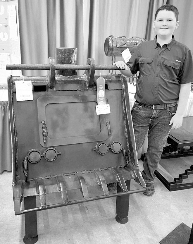 Cooper and his 2025 agricultural mechanics project, a wood-burning stove crafted from an old backhoe bucket, which earned him a blue ribbon at the Oklahoma Youth Exposition, grand champion at the Love County Fair and first place at the Oklahoma State Fair