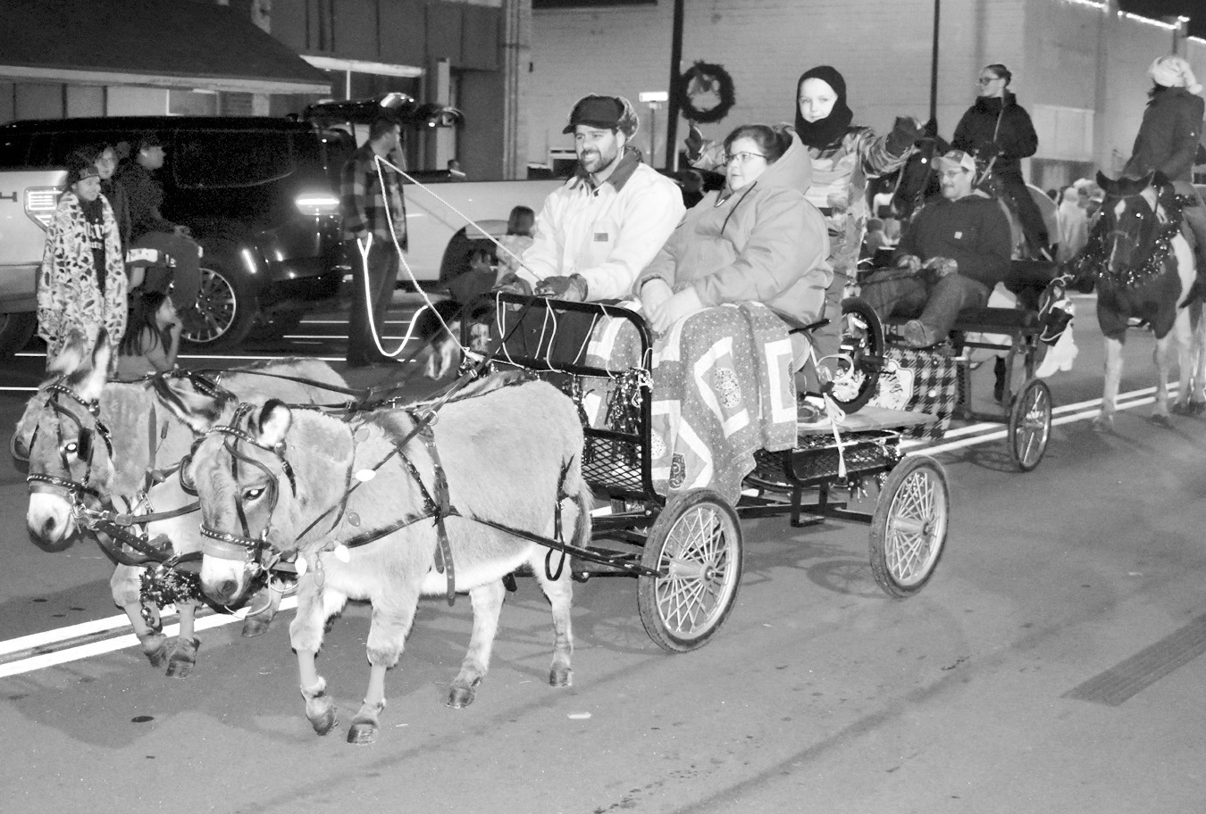 Representatives of Sealock Farms ride in a wagon pulled by a team of donkeys in Saturday evening’s Christmas parade. The event featured multiple entries, including floats, dancers, a marching band and more. The cool weather didn’t deter spectators, as