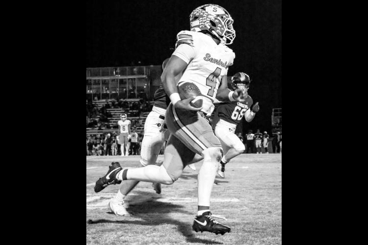 Left, Seminole QB Donavin Garfield scampers towards the end zone in Friday night’s first round playoff game with Heritage Hall. (Photo by Ben Schatzel)