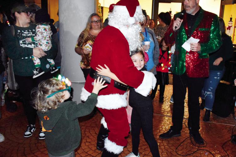 Santa Claus passes out hugs to a group of kids at the Reynolds Wellness Center Thursday night, as a bedazzled Mayor Cory Crabtree announces that Snowman Wonderland is now officially open for the holiday season. —Staff Photo by Andy Wilson