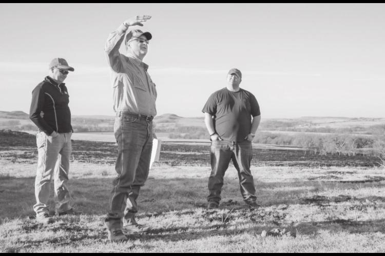 OSU Extension Agricultural Educator Leland McDaniel (center, hand raised) explains the economic and environmental benefits of patch burning at demonstration plots during a multi-county cattle operation field tour. (Photo by Todd Johnson, OSU Agricultural 