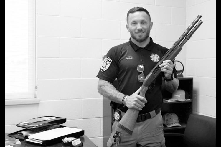 Kingfisher County Sheriff Aaron Pitts stands in his office with the gun initially labeled as missing in an audit by the State Auditor’s Office. (Jake Ramsey/Oklahoma Watch)