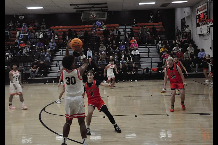 Wewoka Tiger Ladarius Woods shoots from behind the arch over Konawa Tiger Tegun Stalnaker Thursday afternoon. Wewoka won 71-26. Staff Photo by Bill Anderson