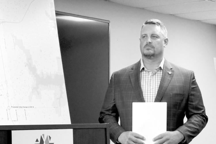 Oklahoma Turnpike Authority Executive Director Joe Echelle on Tuesday stands next to a map of the new route for the South Extension Turnpike in the Norman area. (Photo by Barbara Hoberock/Oklahoma Voice)