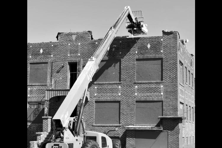 A worker was perched high upon the roof of the Van Sanford Apartments on Milt Phillips Monday as part of a renovation project by GuruStu of Tulsa. The complex sustained heavy damages in the May 2022 tornado. —Staff photo by Andy Wilson