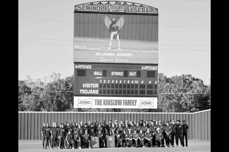 Above, Trojan Baseball players stand beneath the videoboard displaying a photo of teammate Denim Harris (pictured above left) as they hold framed jerseys later presented to his family. A candlelight vigil in honor of Harris was held Tuesday night at the B