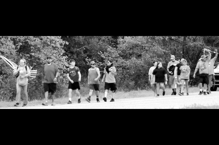 Left, participants in the annual “Every Child Matters Honor Walk” make their way up Highway 377 from the Mekusukey Mission Wednesday morning. The walk focuses attention on Native American children who were forced to leave their homes to attend residential boarding schools. (Photo by Bill Anderson)
