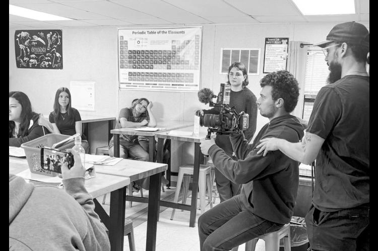 AJ Cutler, IT administrator for The Academies of Oklahoma, assists student Gabe Jones with operating a camera during production of the short film “Stay Awake.” Actors Jaxon Davis, Krislee Tobey, Olivia Bennight and Mia Clark are pictured in the background. (Photo provided)
