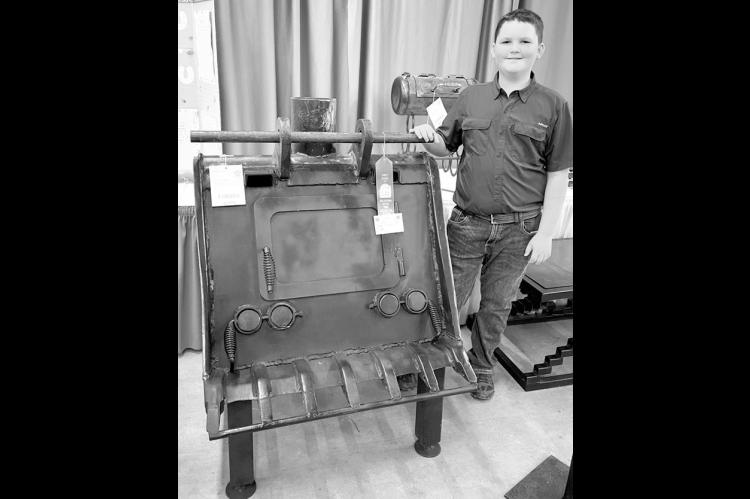 Cooper and his 2025 agricultural mechanics project, a wood-burning stove crafted from an old backhoe bucket, which earned him a blue ribbon at the Oklahoma Youth Exposition, grand champion at the Love County Fair and first place at the Oklahoma State Fair