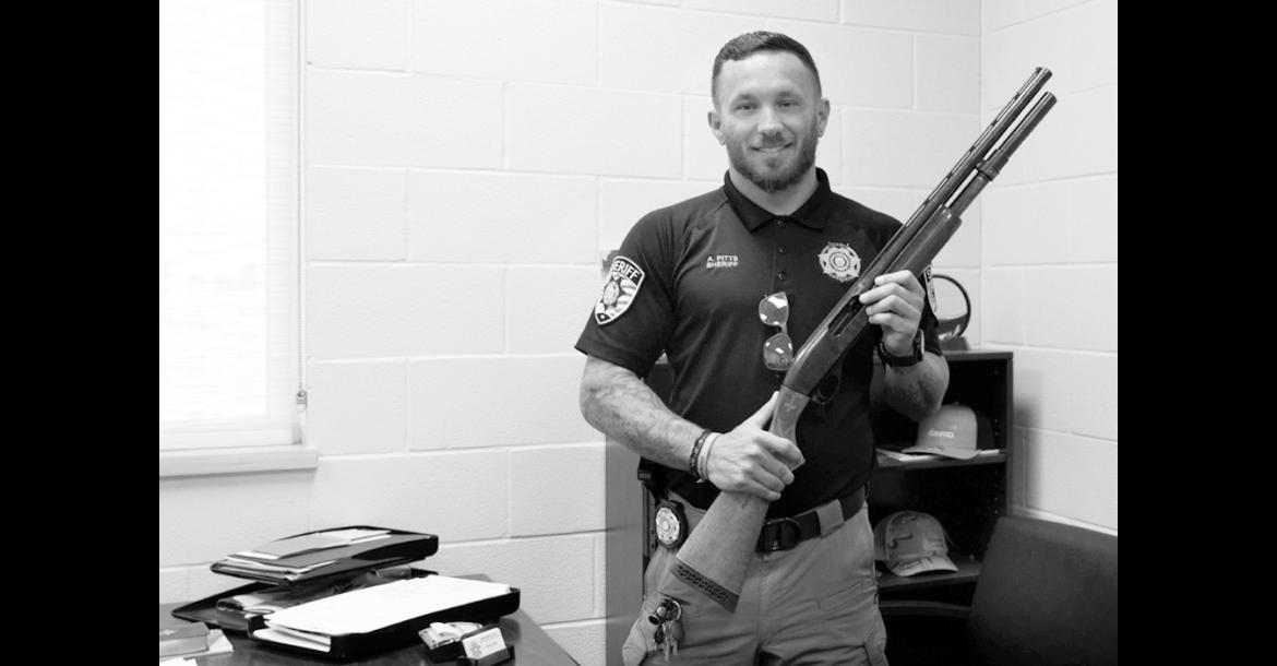 Kingfisher County Sheriff Aaron Pitts stands in his office with the gun initially labeled as missing in an audit by the State Auditor’s Office. (Jake Ramsey/Oklahoma Watch)