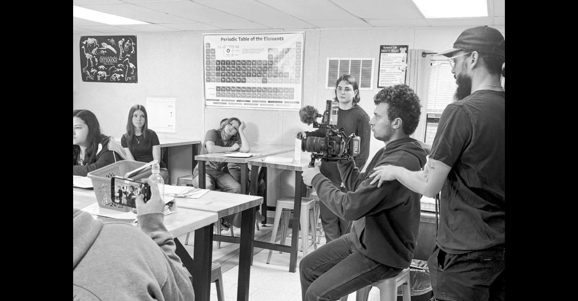 AJ Cutler, IT administrator for The Academies of Oklahoma, assists student Gabe Jones with operating a camera during production of the short film “Stay Awake.” Actors Jaxon Davis, Krislee Tobey, Olivia Bennight and Mia Clark are pictured in the background. (Photo provided)