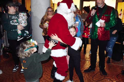 Santa Claus passes out hugs to a group of kids at the Reynolds Wellness Center Thursday night, as a bedazzled Mayor Cory Crabtree announces that Snowman Wonderland is now officially open for the holiday season. —Staff Photo by Andy Wilson