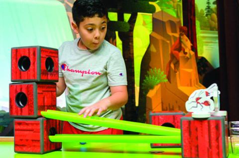 Above: A young visitor gazes in wonder as a vibrant animal comes to life on screen at the FAMily Discovery Center. Below: A young boy explores one of the many hands-on STEAM activities, learning through play in a space designed for imagination and discove