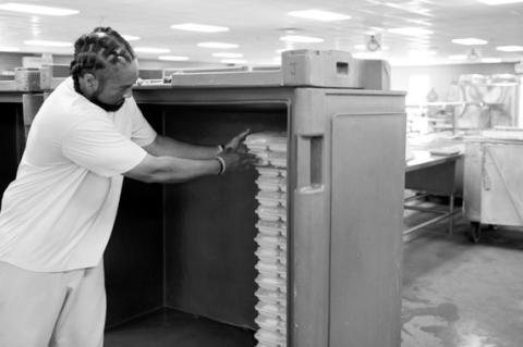 A prisoner stacks food trays in the kitchen of the Joseph Harp Correctional Center on Oct. 10, 2024. (Brent Fuchs/Oklahoma Watch)