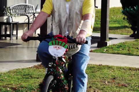 John Christenot, a longtime carrier for the Wewoka Times (a publication of the Seminole Producer), shows off his bicycle which he has decked out with colorful Christmas decorations, including Santa on the handlebars. —Staff photo by Andy Wilson
