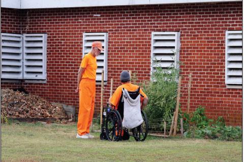 Two prisoners chat near a garden at the John H. Lilley Correctional Center in Boley on Aug. 8, 2025. (Keaton Ross/Oklahoma Watch)